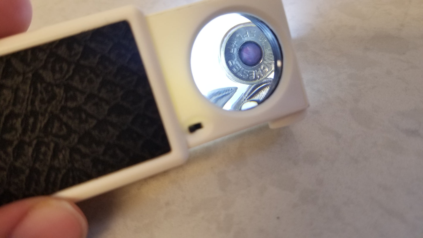 View through 45x Magnifier with Bright White LED Light over jewelry ring. Magnifier enlarges and brightens view of jewelry for identification. LED light switch toggle and non slip grip present. Use as a Jewelry Counterfeit Detector Tool or as a Jewelry Identification Tool. Please visit National Supply Company LLC to purchase Jewelry Magnifier.