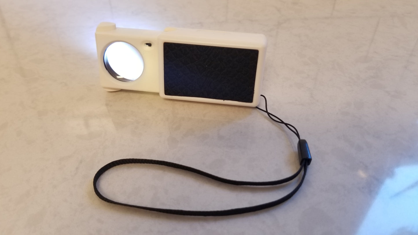 Light Up Magnifier with Wrist Band. Includes Non Slip Grip Pad. Small Magnifying Glass pulled out from protected sleeve. More information available at National Supply Company LLC. a small business local to East Coast America.